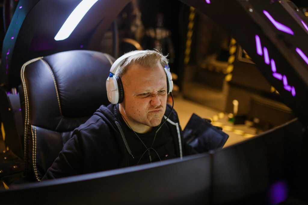 Focused gamer wearing headphones intensely playing an online esports game indoors.