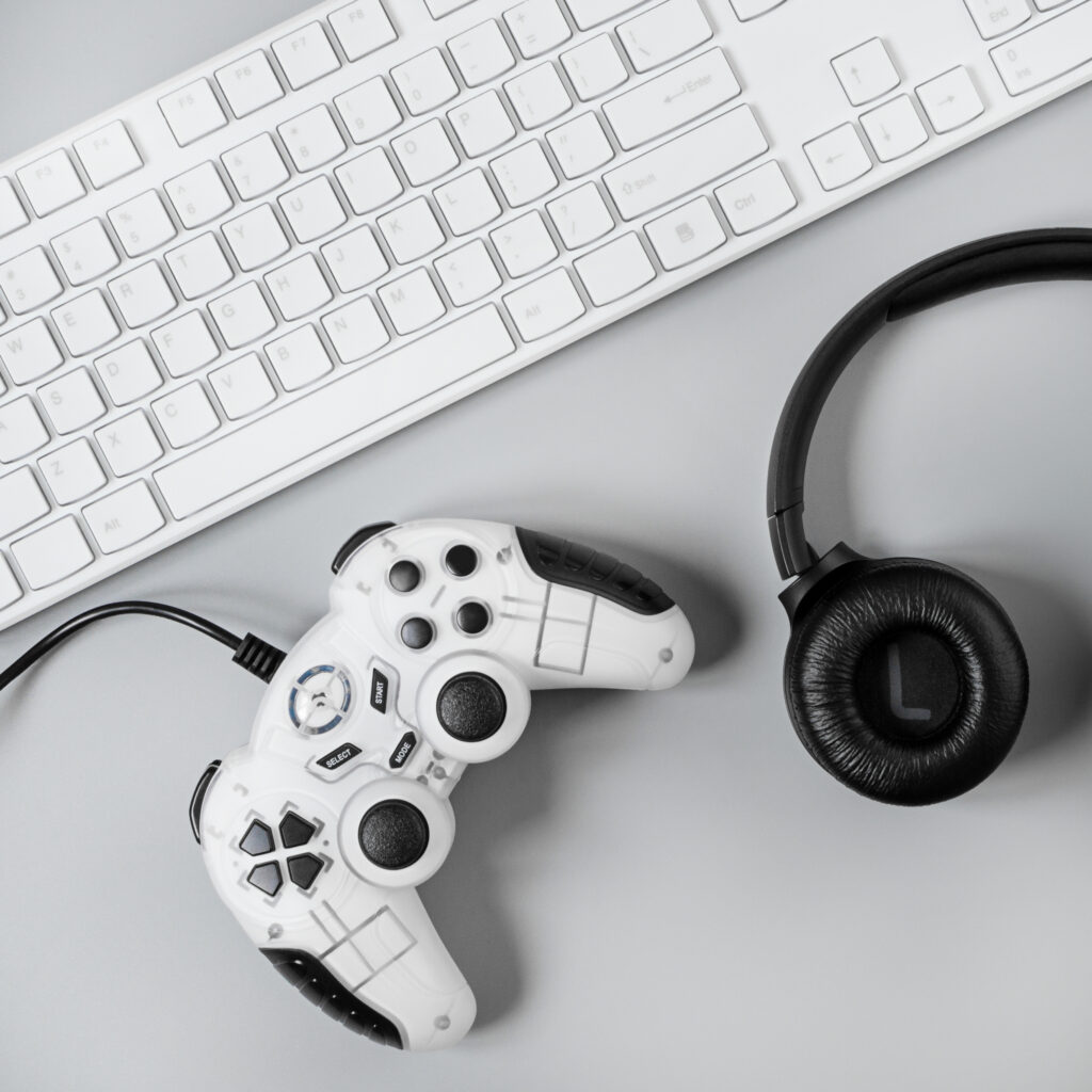 headphones, joystick and keyboard on a gray background. gamer workspace concept, top view a gaming gear